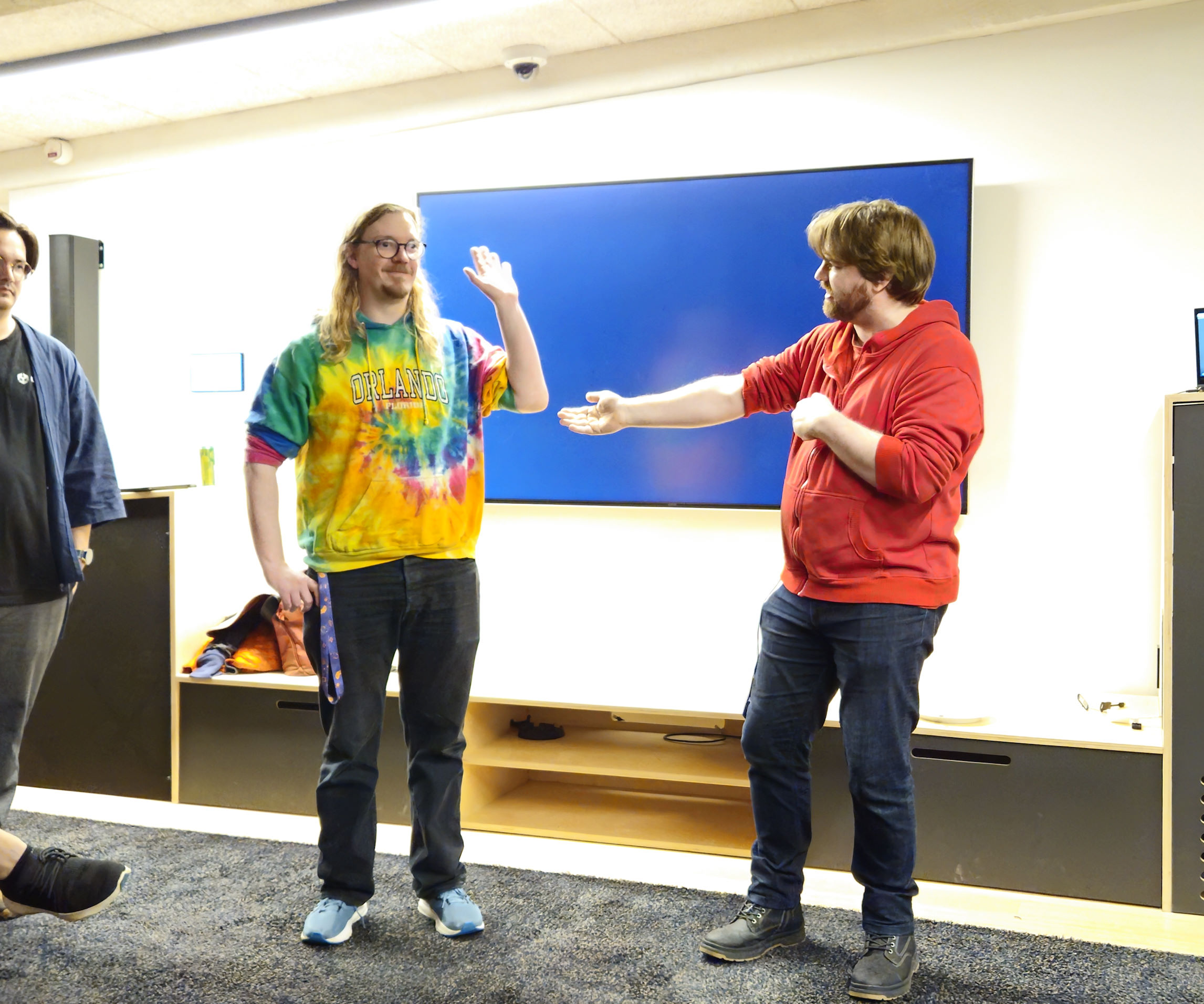 Kristian is in the right side of the image giving a welcome address to a room full of people ready to play games while Alex stands to the left.