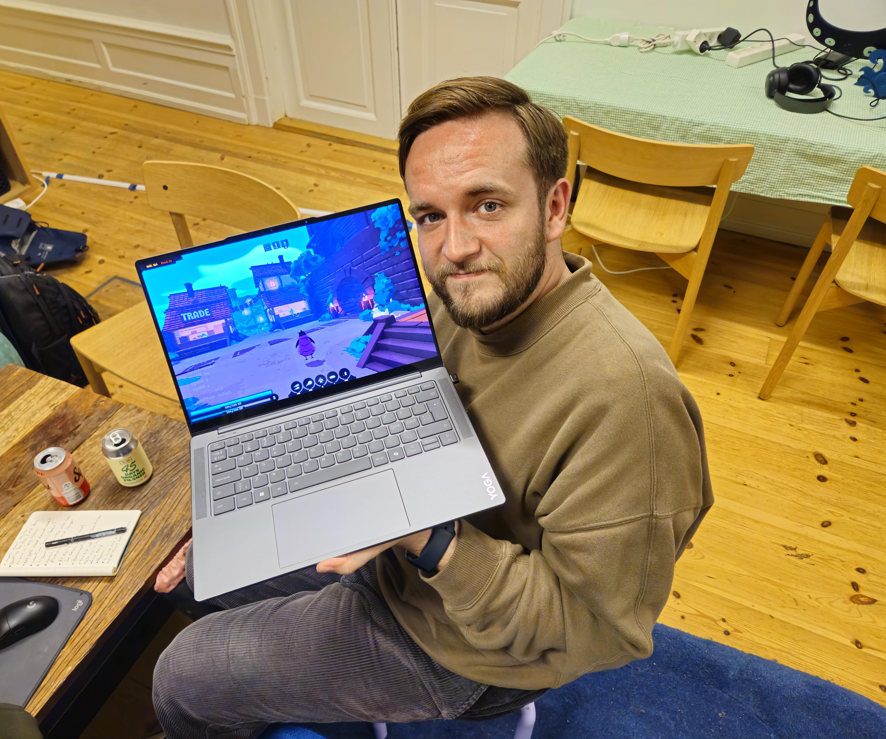 A picture taken from above with Joachim sitting with his laptop showing the game off while looking up at the camera.