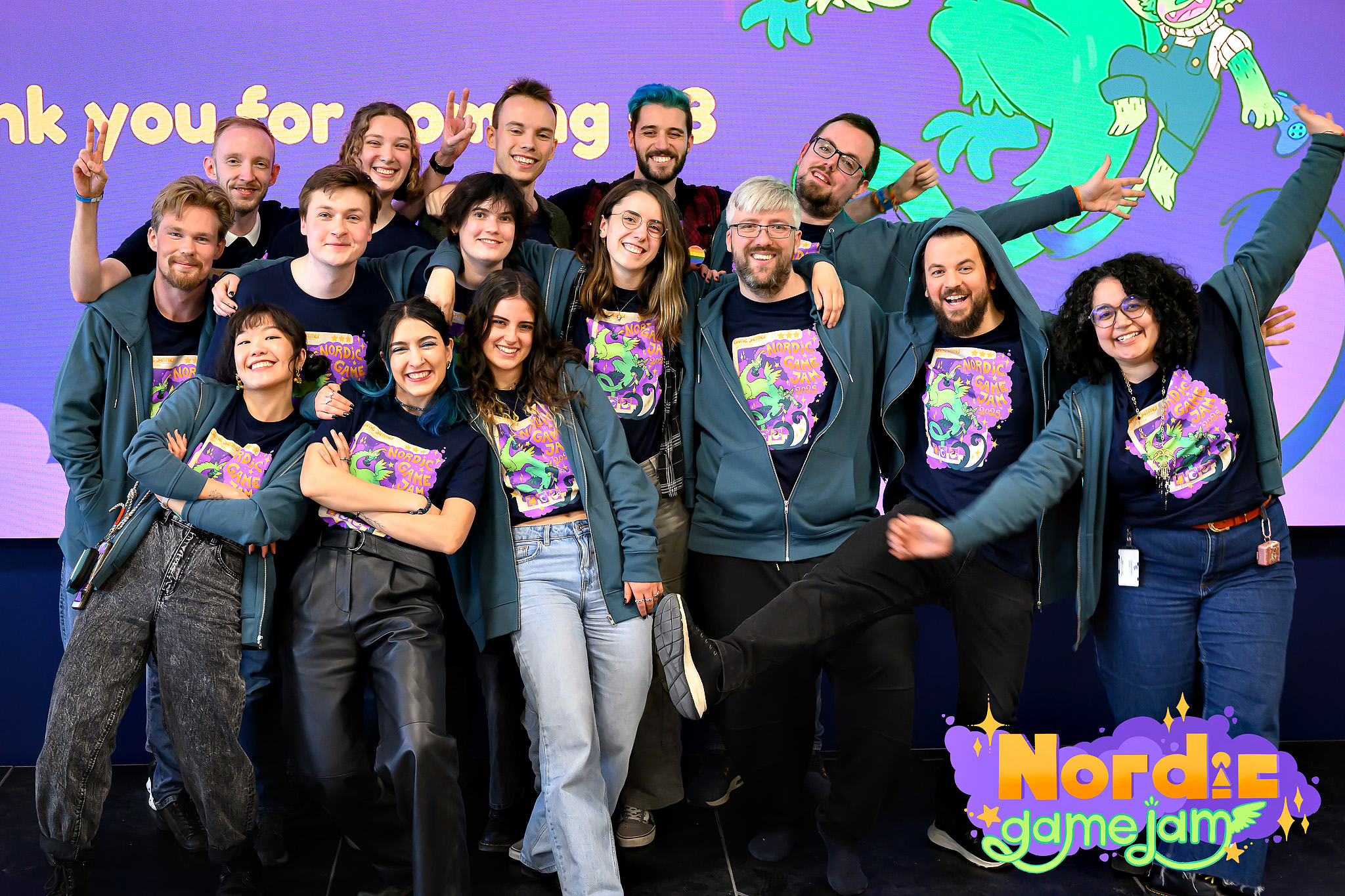 This year's team of organisers all lined up in three rows in front of each other on a scene, smiling and posing.